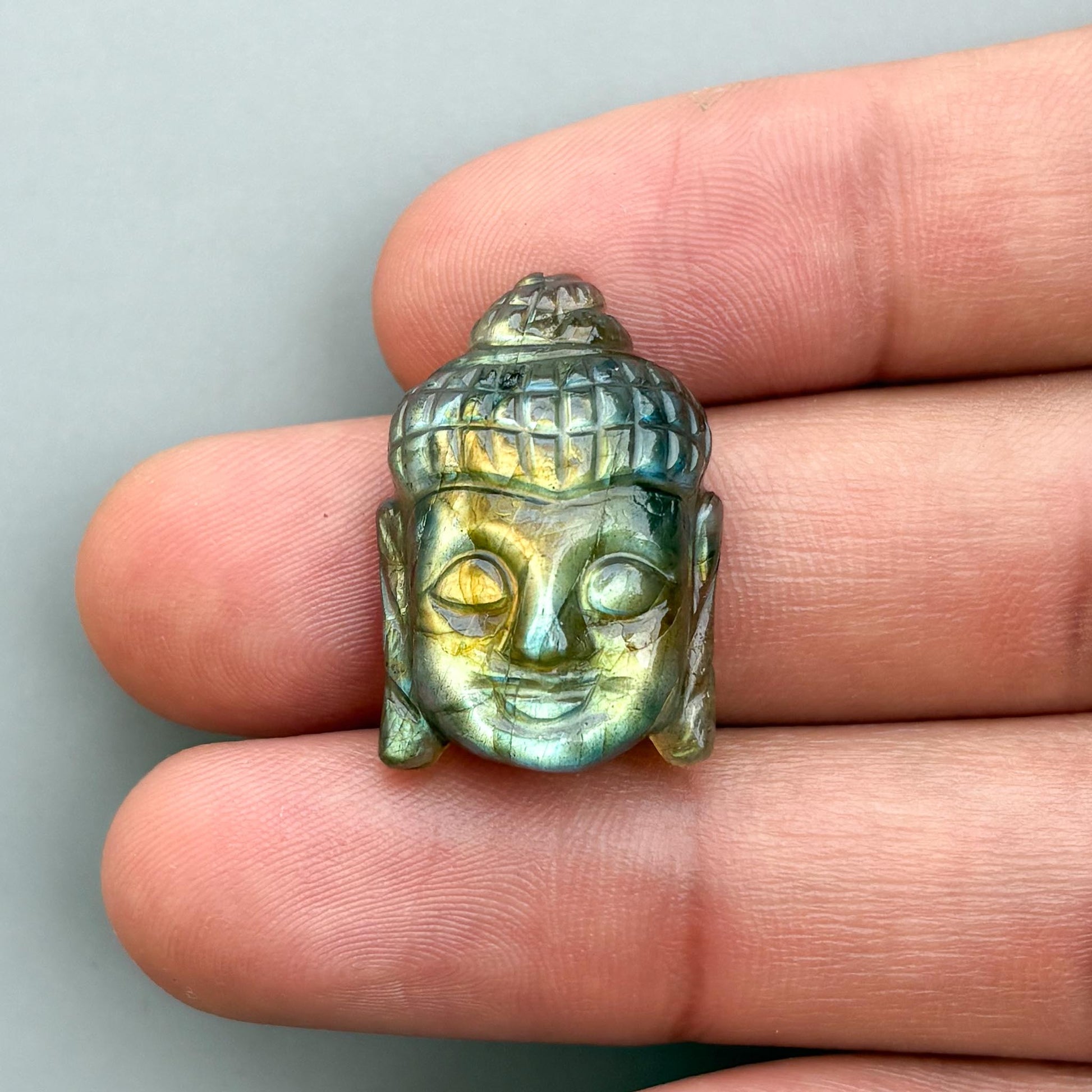 handmade buddha face carving on a labradorite gemstone for jewelry making
